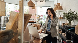 Person in a shop on the phone with a laptop