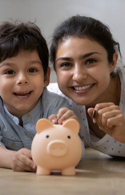 Child and parent drop coins in piggybank