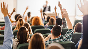 Students raising hands in college lecture hall