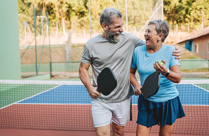 Older Couple walking off a pickle ball court