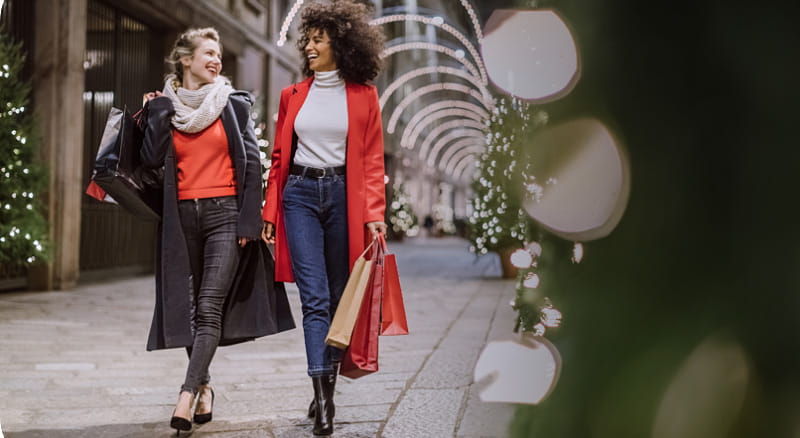 Two women walking down the street with shopping bags
