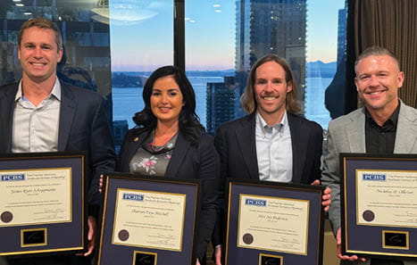 Four Banner Bank employees with framed banking certificates