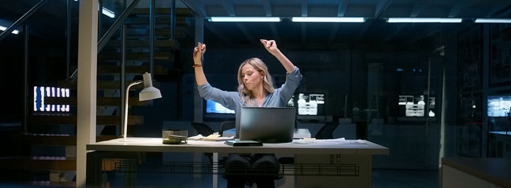 Person celebrating at computer in dark office