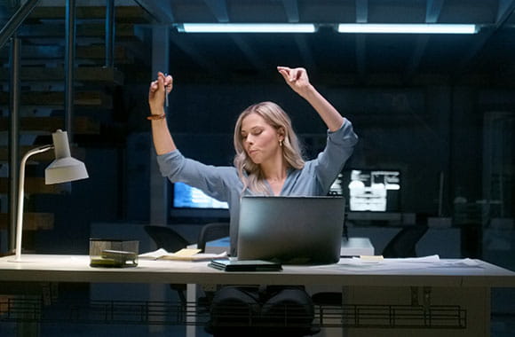 Person celebrating at computer in dark office