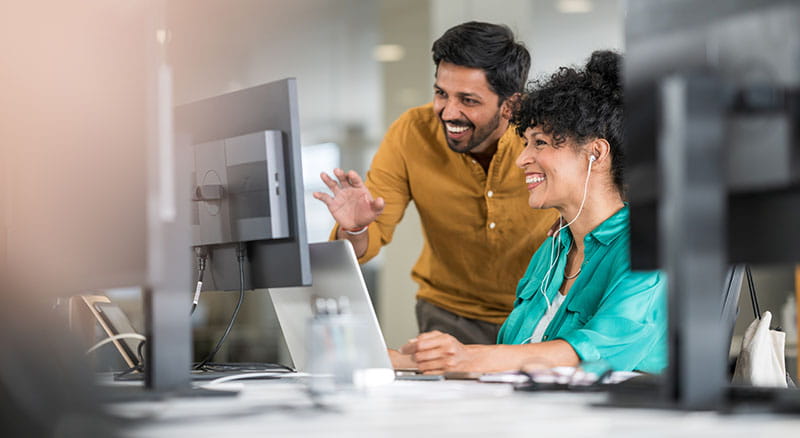Two people looking at a computer and smiling