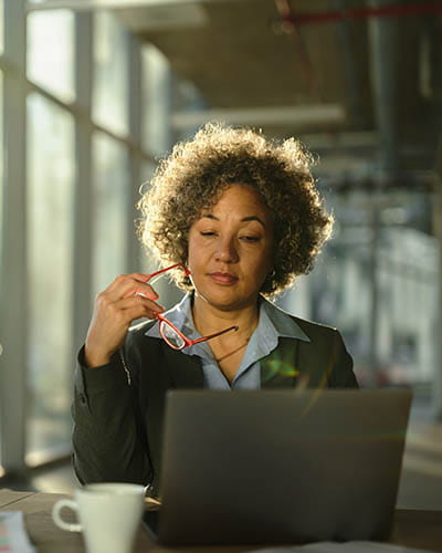 Person holding glasses and looking at a laptop