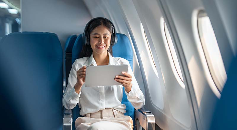 Person on a plane with a tablet and headphones