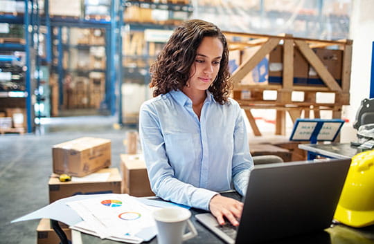 Woman in warehouse working on laptop