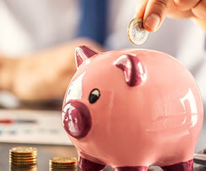 hand putting a coin in a piggy bank