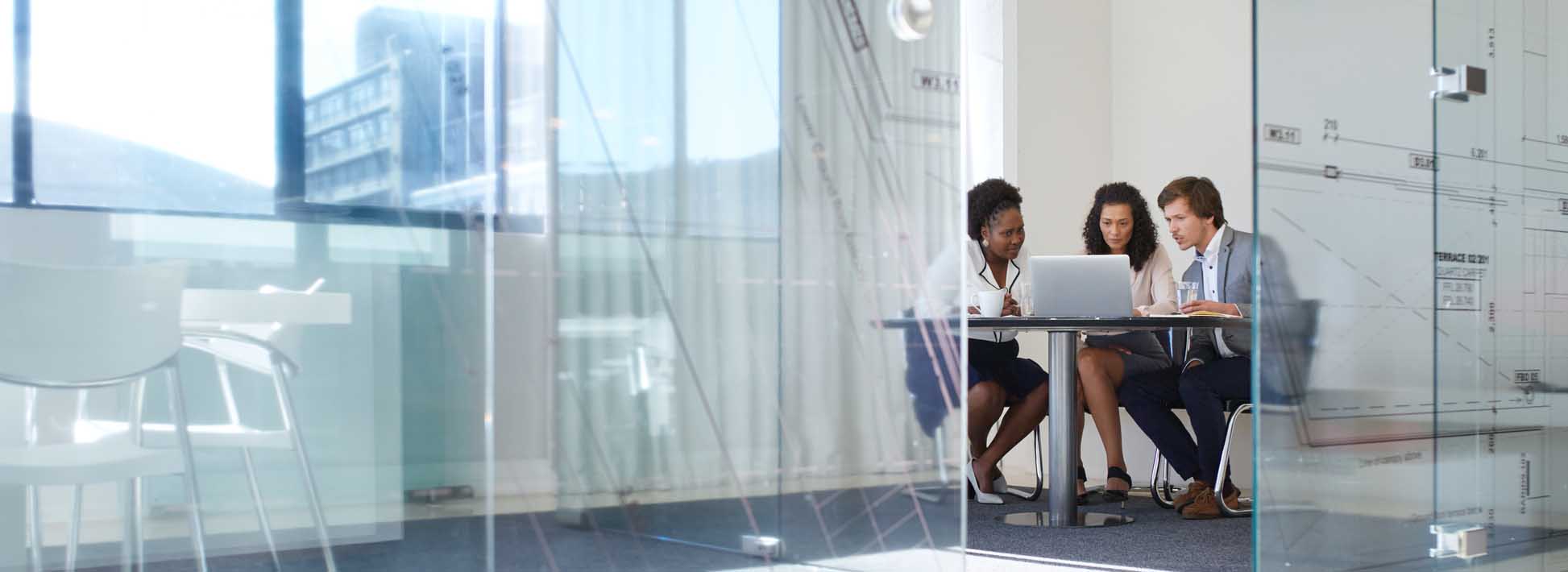 Three people at a table in a large office