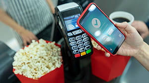 Person paying for popcorn with digital wallet on iphone