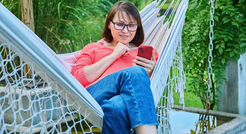 Woman in hammock looks at smart phone