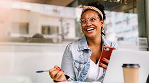 Person smiling with phone and pen in hand