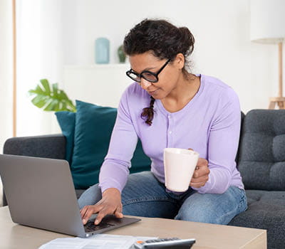 women at laptop and sipping coffee