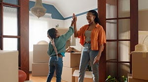 Mother and daughter high fiving in home with moving boxes