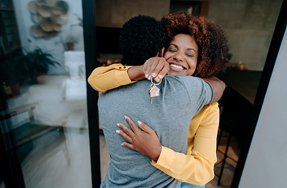 Two people hugging outside of home with keys