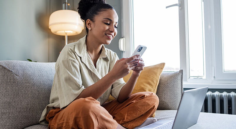 Person on couch with phone and laptop