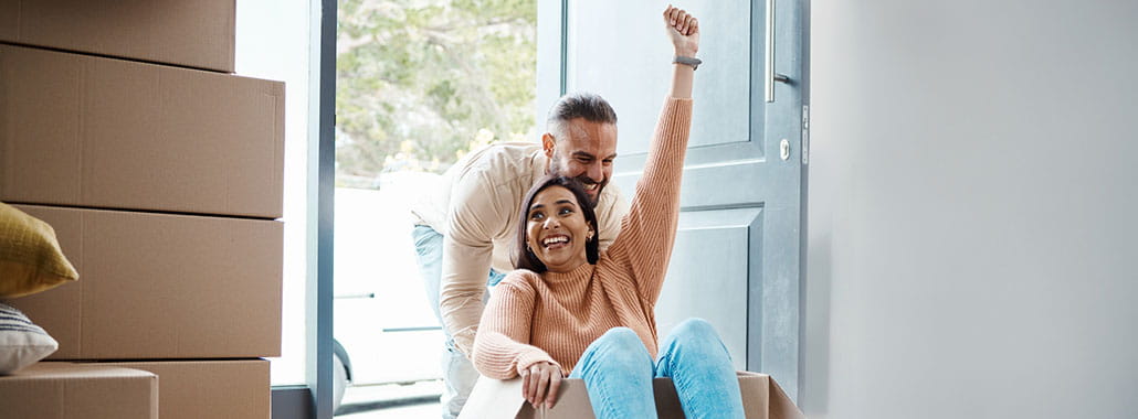 Person pushing another person in a moving box into a home