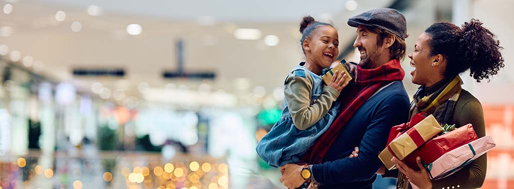 Family smiling with presents at a shopping mall