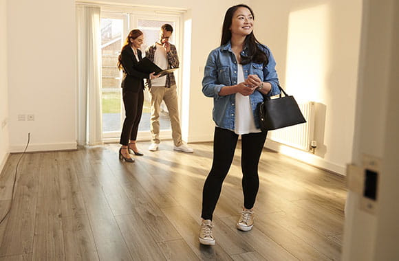 Person looking at empty house with another looks at paperwork with an agent