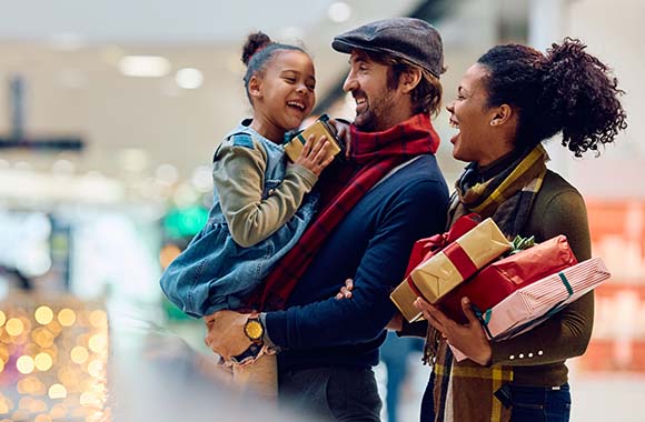 Family smiling with presents at a shopping mall