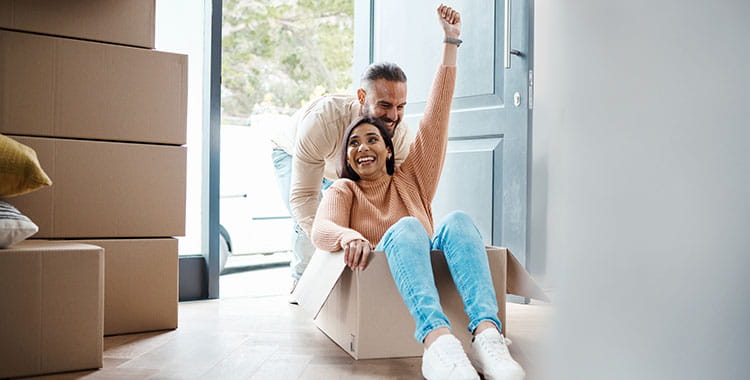 Person pushing another person in a moving box into a home