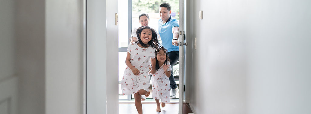Children running into a house while parents hold the door open