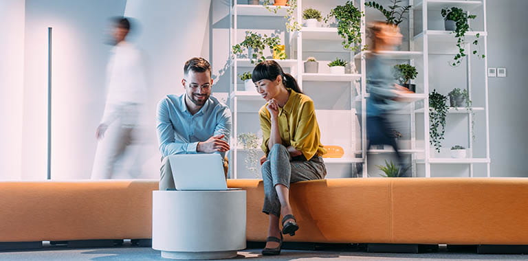 Two colleagues in an office space looking at a laptop