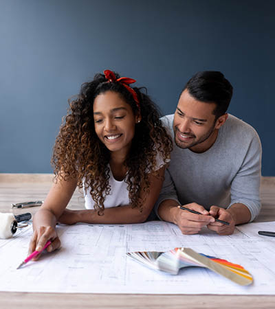 woman and man looking at house plans on the floor
