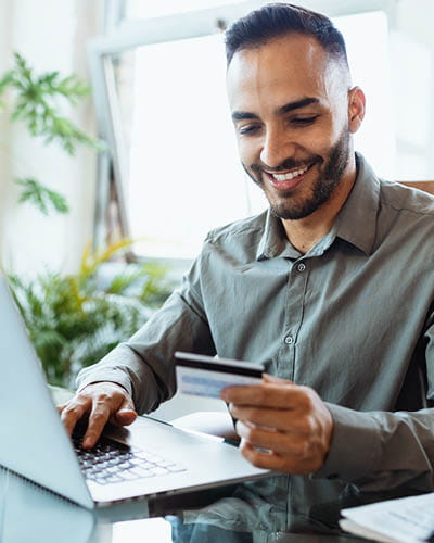 A guy at a computer with his debit card