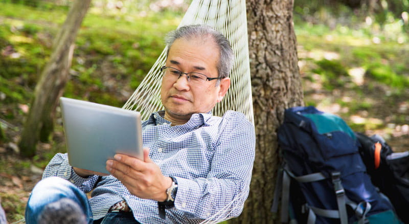 Man reading tablet while relaxing on hammock
