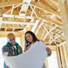 Man and woman review design plans while standing in a home construction financed by Banner Bank