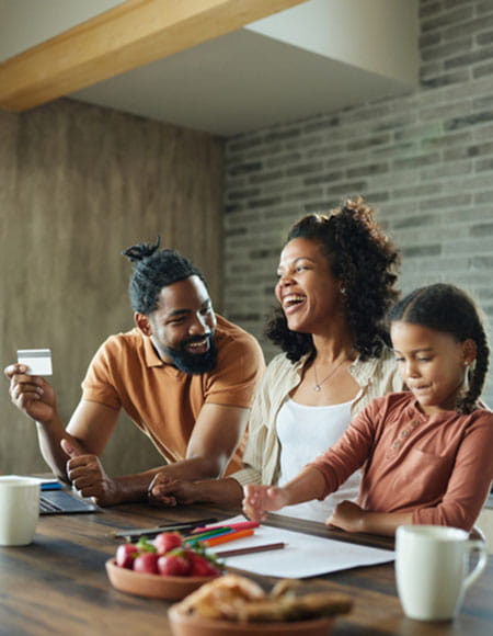Family smiling while holding a card at a table