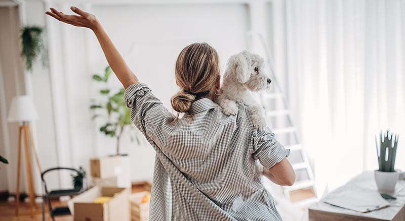 Person and dog with arm in the air looking at new home