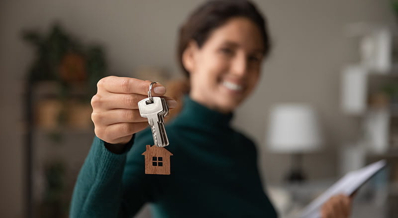 Woman holding a key with house keychain
