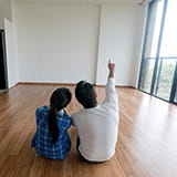 Couple on the floor of empty house looking at remodel options