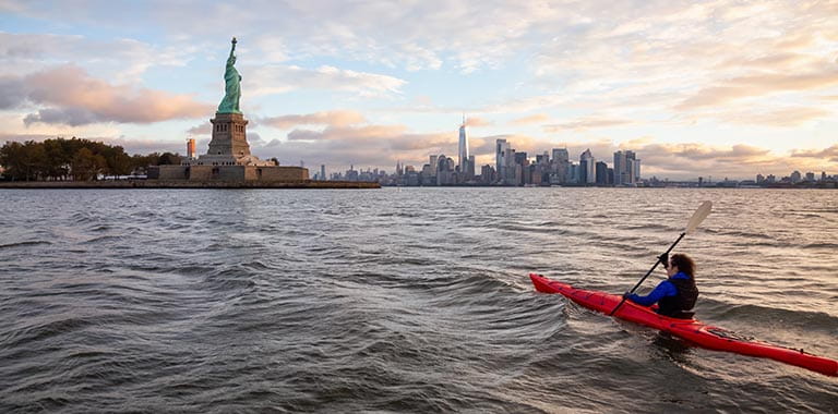 Person kayaking up to Statue of Liberty