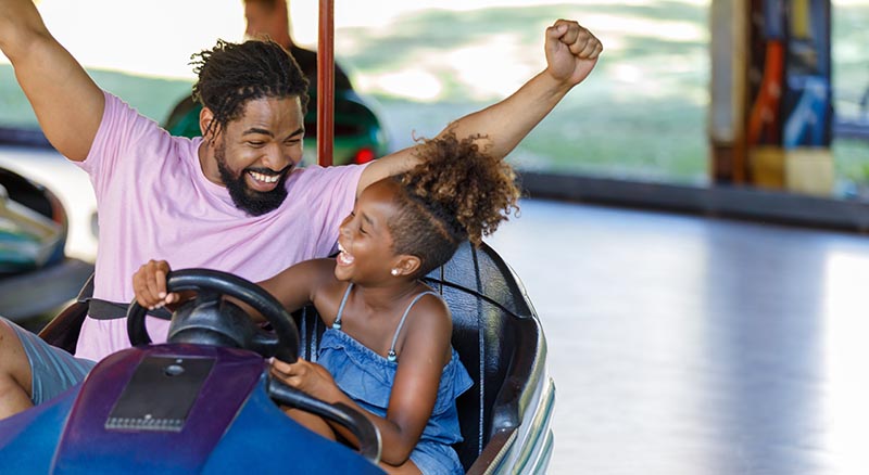 Father and daughter having fun driving a bumper car