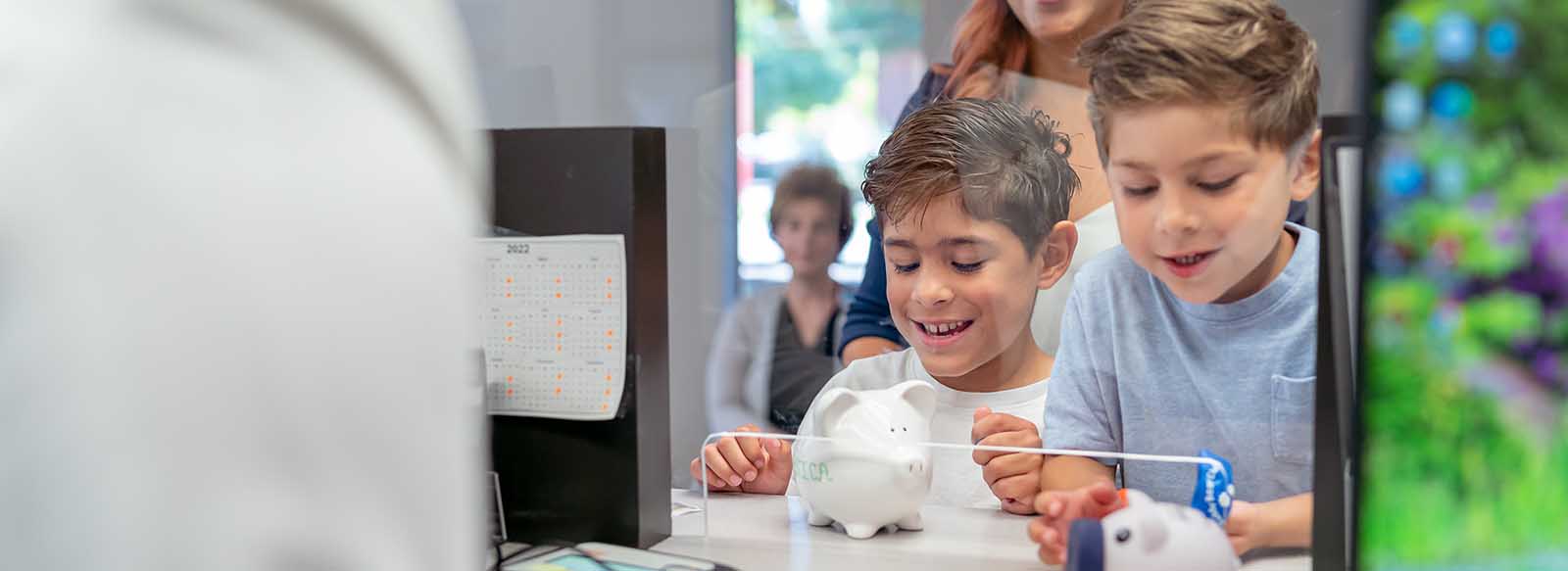 Two kids depositing piggy bank coins