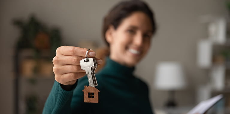 Woman holding a key with a house keychain